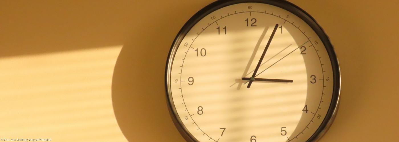 Eine Wanduhr, die einen Schatten auf eine Wand wirft