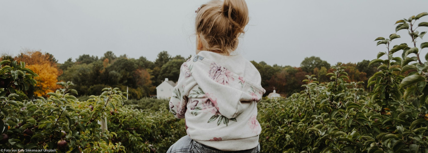 Foto eines Mädchens, das auf der Schulter einer Person reitet