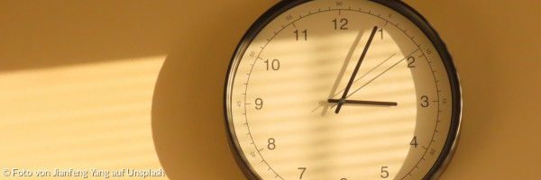 Eine Wanduhr, die einen Schatten auf eine Wand wirft