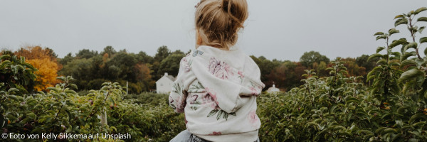 Foto eines Mädchens, das auf der Schulter einer Person reitet