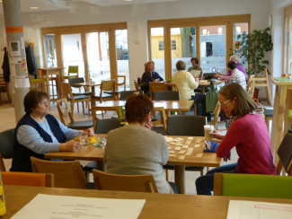 Besucherinnen des Café sitzen am Tisch, spielen und trinken Kaffee